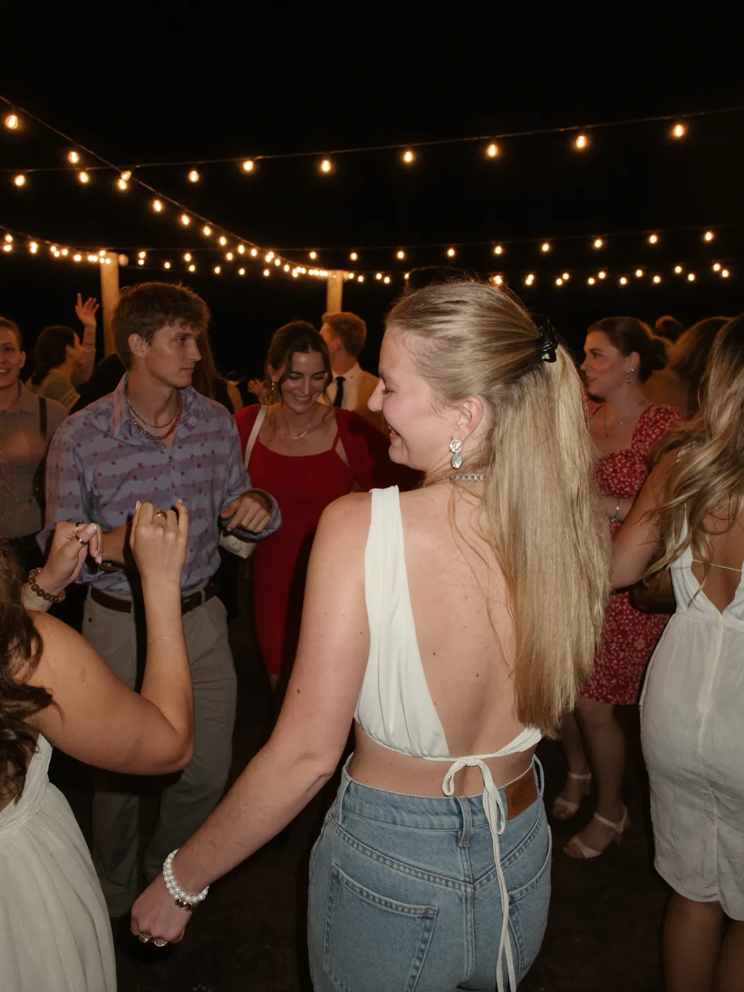 Amigos bailando bajo luces de verbena en una boda de noche