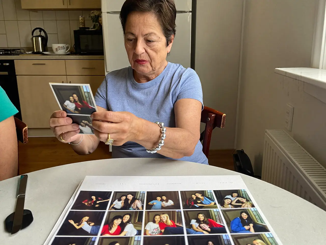 Una abuela repasa fotos impresas de la fiesta en su mesa de la cocina